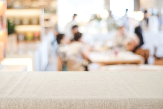 Leeren Sie Tischplatte mit Leinentischdecke über unscharfem Café mit bokeh Hintergrund