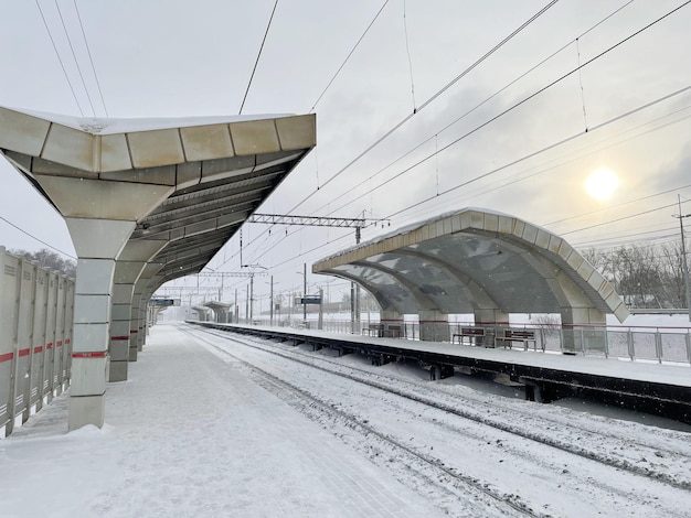 Leerer Bahnsteig ohne Passagiere im Winter bei Sonnenuntergang. Eisenbahn, Konzept für kaltes Wetter