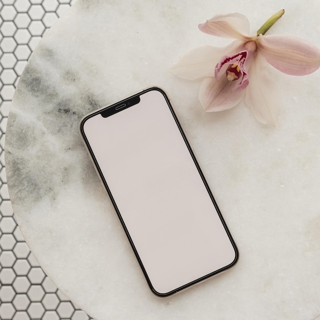 Leerer Beschneidungspfad-Bildschirm Handy rosa Blume auf Marmorsteintisch auf Mosaikfliesenhintergrund Ästhetische Vorlage mit Mockup-Platz Draufsicht auf flache Lage