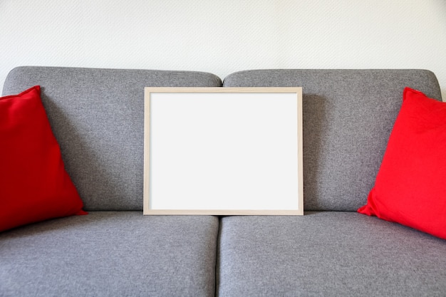 Leerer Bilderrahmen auf einem Sofa. Minimalistisches Interieur