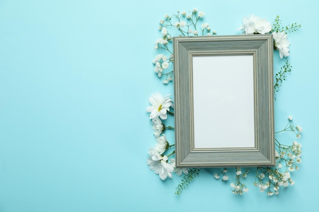 Leerer Bilderrahmen mit Blumen auf blauem Hintergrund