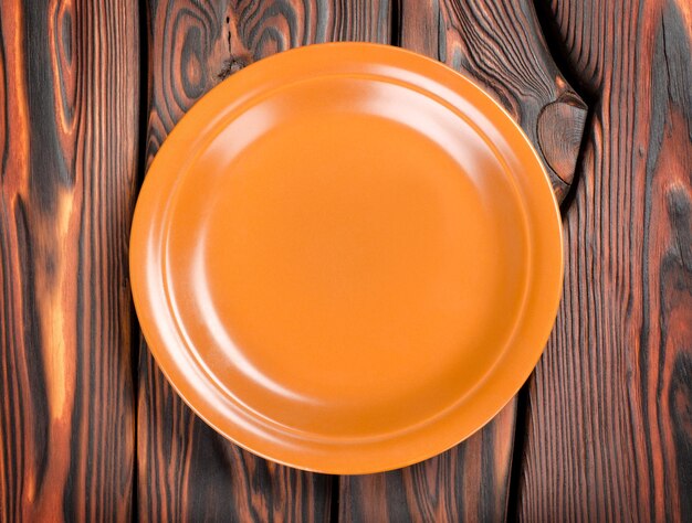 Leerer brauner Teller auf einem Holztisch