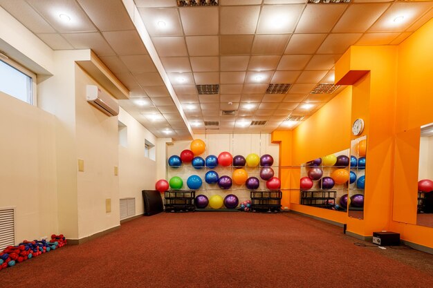 Foto leerer, geräumiger fitnessraum mit fitballs an der wand und hanteln auf dem boden