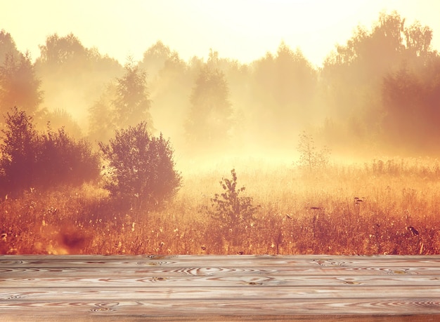 Leerer Holztisch auf einem Goldhintergrund mit einem aufgehende Sonne.