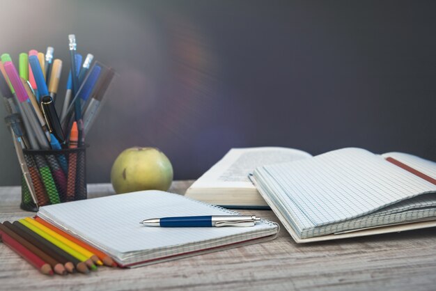 Leerer Notizblock auf Lehrertisch gegen Tafel. Bildungskonzept.