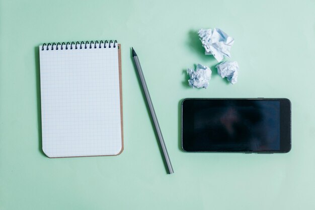 Leerer Notizblock und Telefon auf blauem Raum mit Stift.