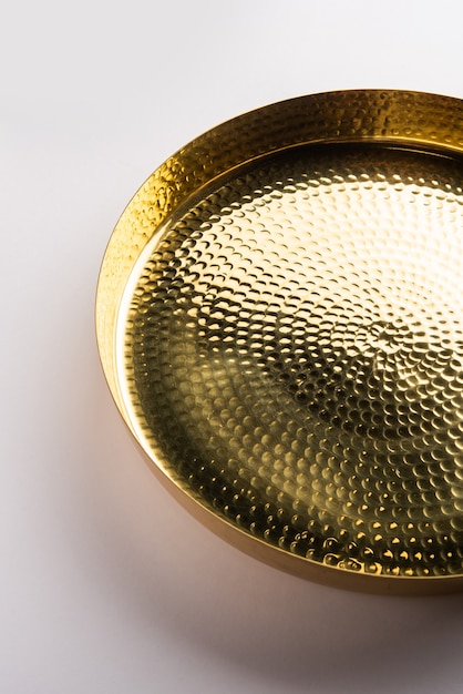 Leerer ovaler oder runder Thali oder Teller aus Messing, Ppital oder Gold auf weißer Oberfläche