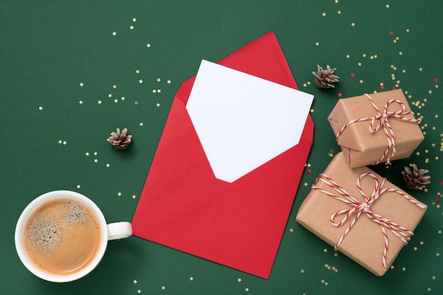 Leerer quadratischer Papiermodellumschlag rot, goldene Sterne Konfetti, Geschenkboxen auf grünem Hintergrund.