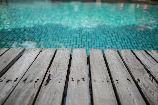 leerer Raum verwitterter hölzerner Terrassenboden neben blauem Swimmingpool für Montagegegenstand