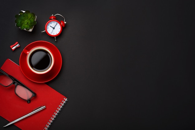 Leerer Raumdesktop der schwarzen Kaffeetasse-Notizblockweckerblume des Hintergrundes roten