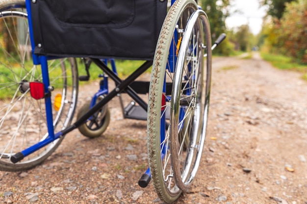 Leerer Rollstuhl, der auf der Straße steht und auf Patientendienste wartet. Ungültiger Stuhl für Behinderte, der im Freien in der Natur geparkt wurde. Behindertengerechtes Symbol. Medizinisches Konzept des Gesundheitswesens.