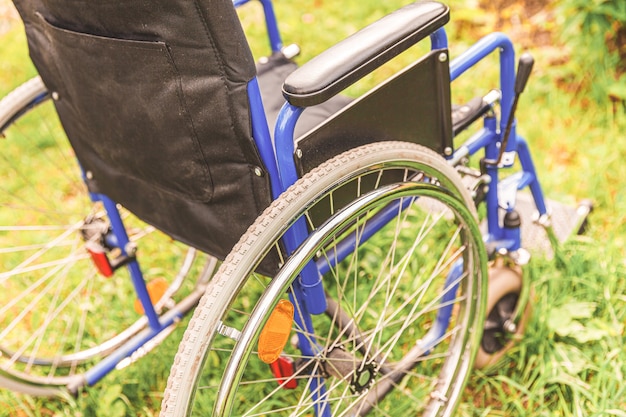 Leerer Rollstuhl, der auf Gras im Krankenhauspark steht und auf Patientendienste wartet