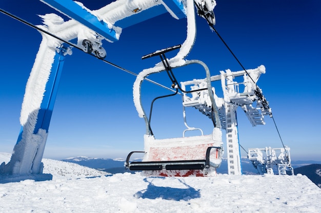 Leerer Skilift mit Frost und Schnee mit Bergen bedeckt