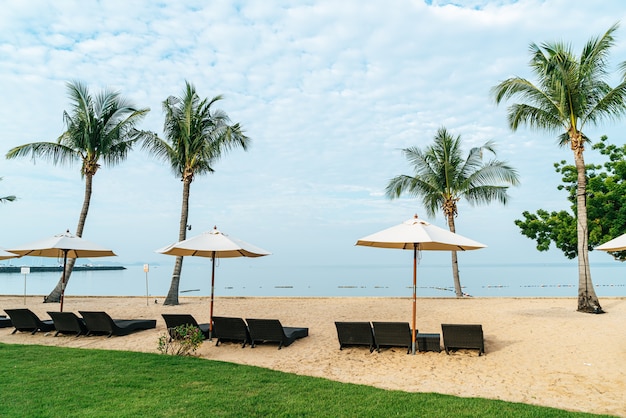 leerer Strandkorb mit Palme am Strand mit Meer