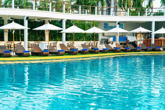 leerer Strandkorb mit Sonnenschirm um den Pool