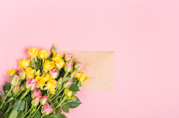 Leerer Umschlag mit Platz für Text für Frühlingsgrußkarte. Rosen auf rosa Hintergrund. Flache Lage, Draufsicht