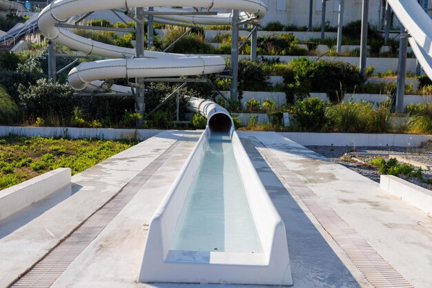 Leerer Wasserpark mit hohen weißen Rutschen und weißen Sonnenliegen