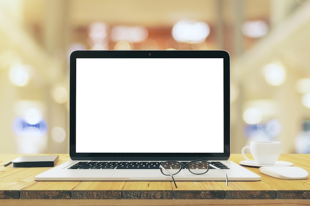 Leerer weißer Laptop-Bildschirm mit Brille und Tasse Kaffee auf Holztisch-Attrappe