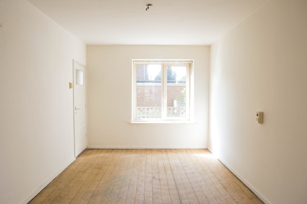 Leerer weißer Raum mit Holzparkettboden vor der Renovierung alt leer