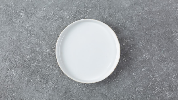 Leerer weißer Teller auf grauem Betonhintergrund
