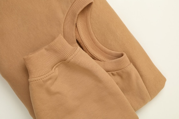 Leeres beige gefaltetes Sweatshirt auf weißer Oberfläche