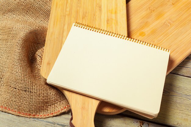 Leeres Blatt des geöffneten Notizblockes und der Küchengeräte auf Tabelle mit Tischdecke, Kopienraum