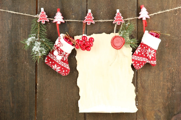 Leeres Blatt mit Weihnachtsdekor, das an grauer Holzwand hängt