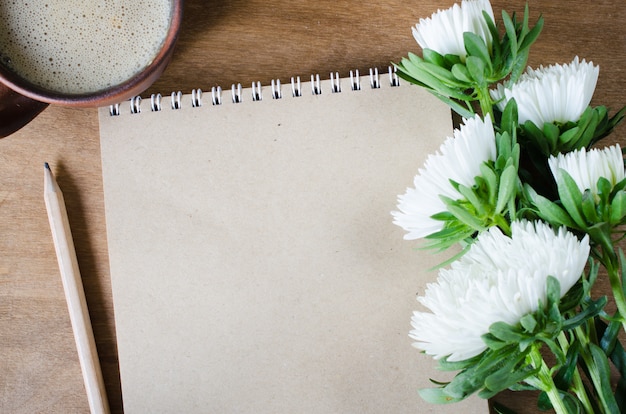 Leeres braunes Notizbuch mit Herbstblumen.