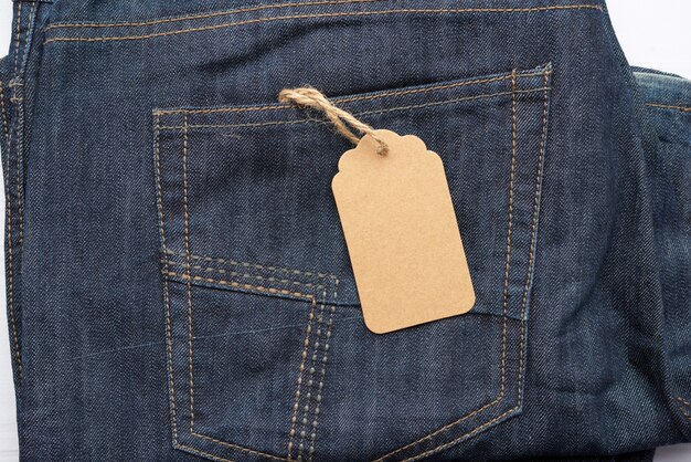 Leeres braunes rechteckiges Etikett in der Gesäßtasche der blau gefalteten Jeans