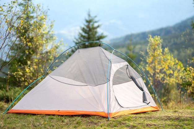 Leeres Campingzelt, das auf Campingplatz mit Blick auf majestätische hohe Berggipfel in der Ferne steht. Wandern in wilder Natur und aktives Wanderkonzept.