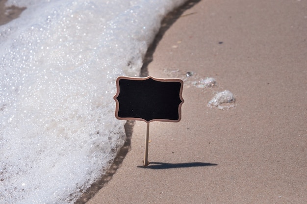 Leeres hölzernes schwarzes Zeichen auf dem Strand