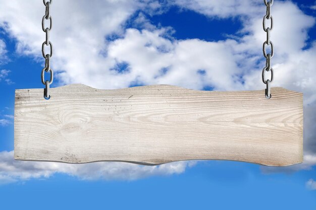 Leeres Holzbrett, das an Ketten hängt, mit bewölktem Himmel im Hintergrund