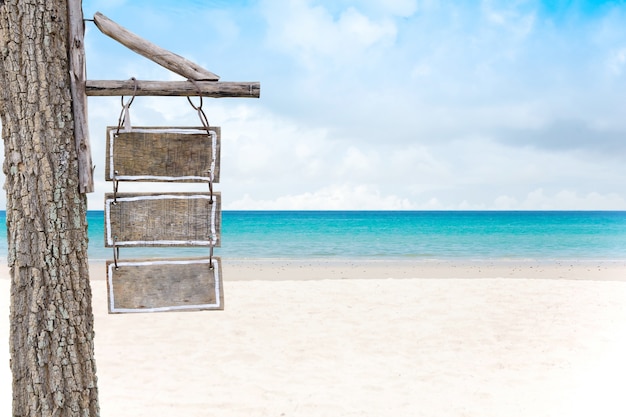 Leeres Holzschild auf einem Sandstrand und einem schönen Seehintergrund im Sommer.