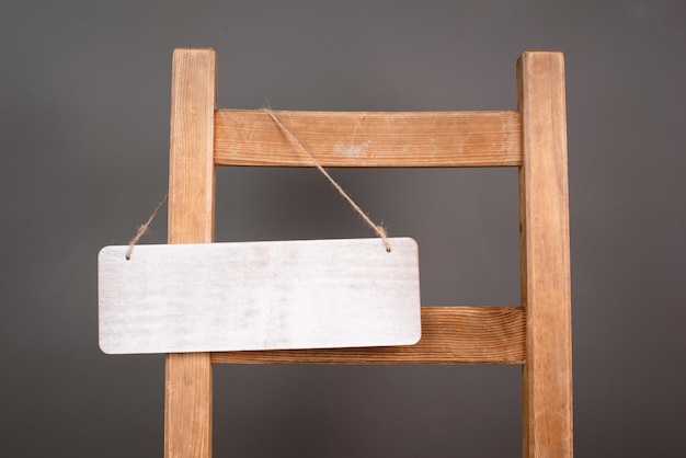 Leeres Holzschild hängt an einem Stuhl, Willkommens- und Verkaufskonzept, offenes und geschlossenes Geschäft