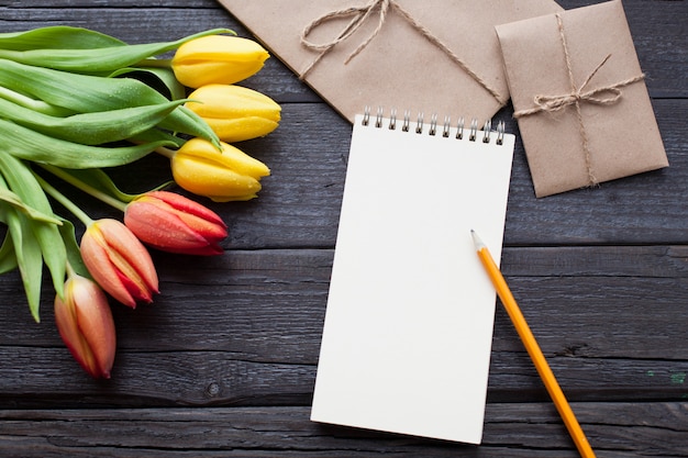 Leeres Notizbuch, Bleistift und gelbe Tulpen.