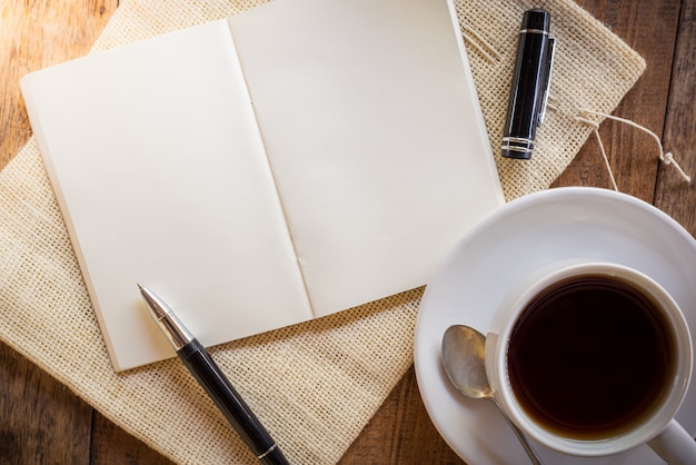 Leeres Notizbuch mit Stift und Tasse Kaffee