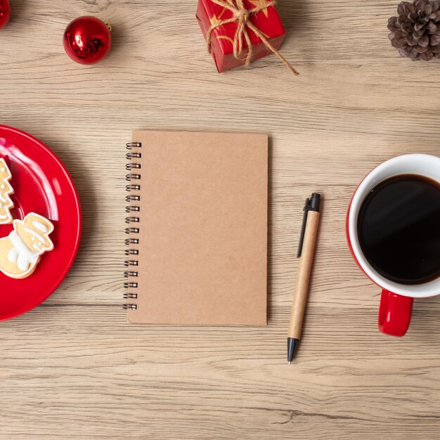 Leeres Notizbuch, schwarze Kaffeetasse, Weihnachtsplätzchen und Stift auf Holztisch, Draufsicht und Kopienraum. Weihnachten, Frohes neues Jahr, Ziele, Auflösung, Aufgabenliste, Strategie und Plankonzept