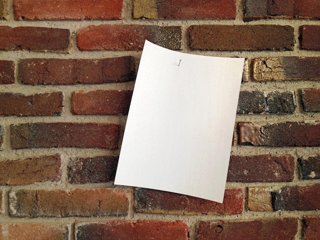 Leeres Papier hängt an einer Ziegelsteinmauer