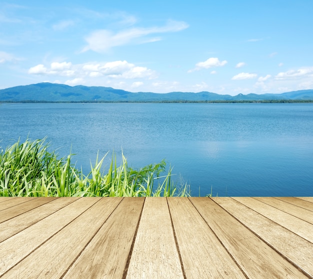 Leeres Perspektivenholz über See und Hintergrund des blauen Himmels