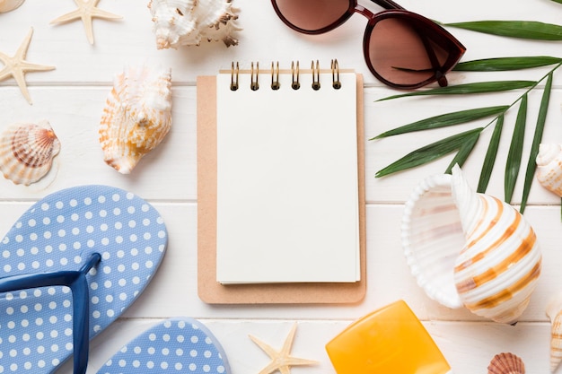 Leeres Schreibbuch mit sommerlichen Strandaccessoires auf Hintergrundkopierraum Flach lag mit Kopierraum