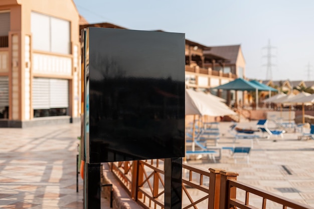 Leeres schwarzes Schild für Text und Design am Strand. Werbung mit freiem Platz für Logo auf der Straße.