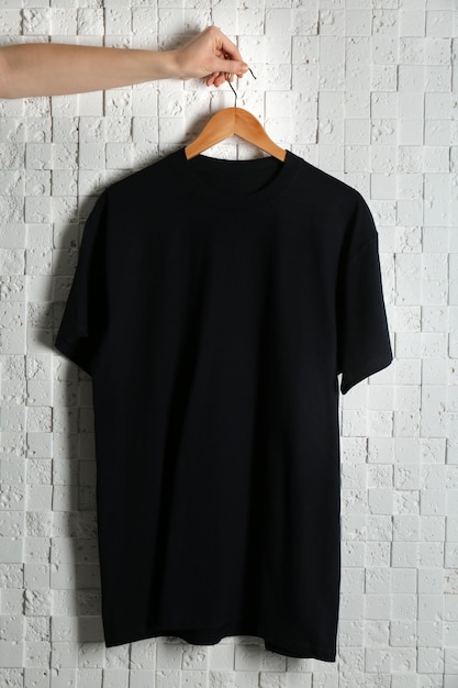 Leeres schwarzes T-Shirt gegen einen hellen Hintergrund