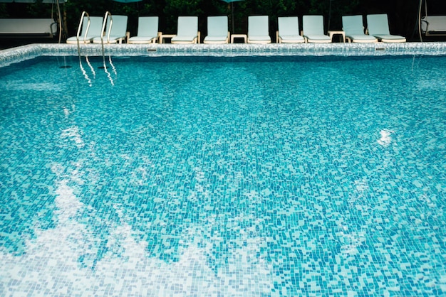 Leeres Schwimmbad mit blauen Mosaikfliesen ohne Menschen Ein Ort für Sommerurlaub und Entspannung Liegestühle am Pool des Hotels Badeplatzkonzept des Hotels