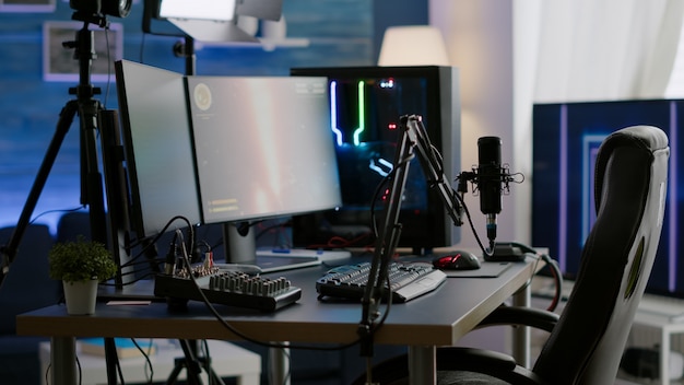 Leeres Streaming-Studio mit RGB-LED-Leuchten, leistungsstarkem PC für Online-Gaming-Wettbewerbe. Display mit Stream-Chat für virtuelles Turnier vorbereitet, Wohnzimmer mit niemandem in