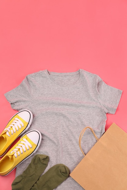 Leeres T-Shirt, Tasche, Turnschuhe und Socken auf rosa Hintergrund