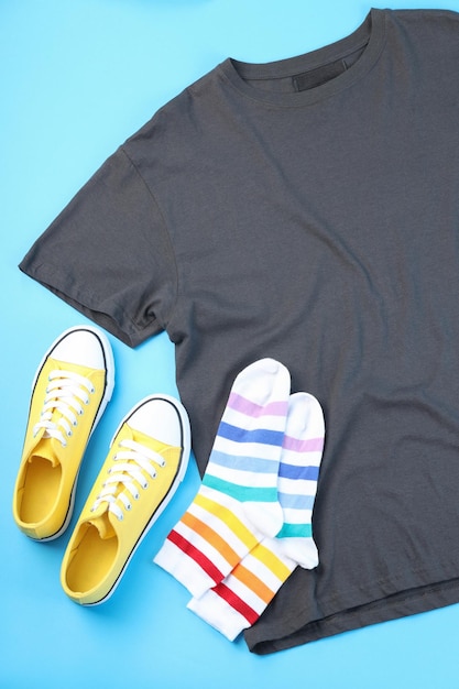 Leeres T-Shirt, Turnschuhe und Socken auf blauem Hintergrund