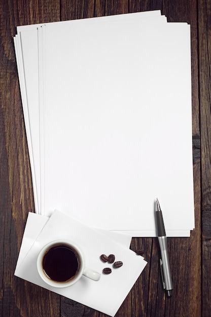 Leeres weißes Blatt Papier und eine Tasse Kaffee auf dunklem Holztisch, Ansicht von oben