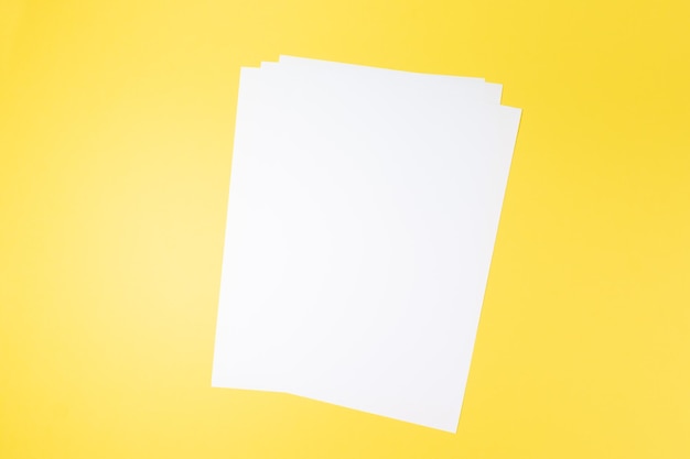Leeres weißes Papierblatt und ein Stift auf gelbem Hintergrundmodell