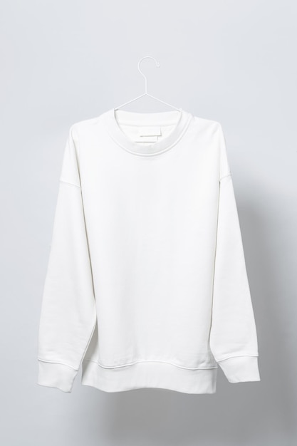 Leeres weißes Sweatshirt, das am dünnen metallischen Kleiderbügel vor hellgrauem Hintergrund hängt