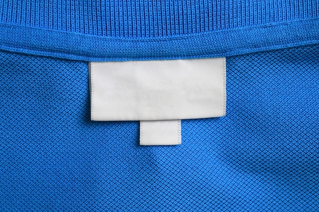 Foto leeres weißes wäschekleidungsetikett auf blauem hemdstoff-hintergrund